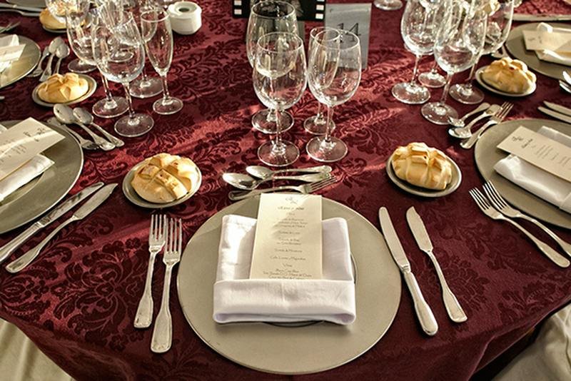 Detalle de mesa elegantemente decorada con mantel carmesí